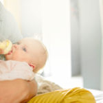 Baby im Arm mit Milchpumpe slider